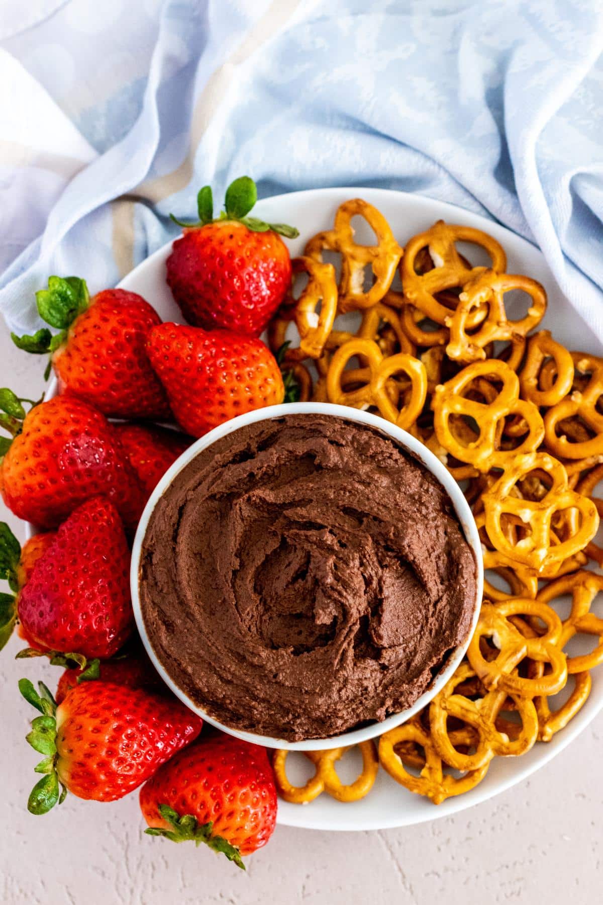 Platter with strawberries, bowl of chocolate hummus, and mini pretzels.
