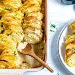 Casserole dish with scalloped potatoes and serving spoon.