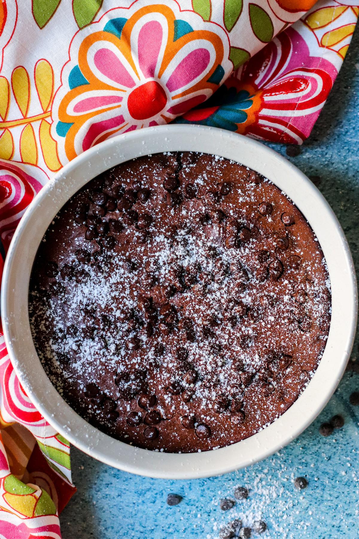 Brownies in a ceramic baking dish topped with powdered sugar and mini chocolate chips.