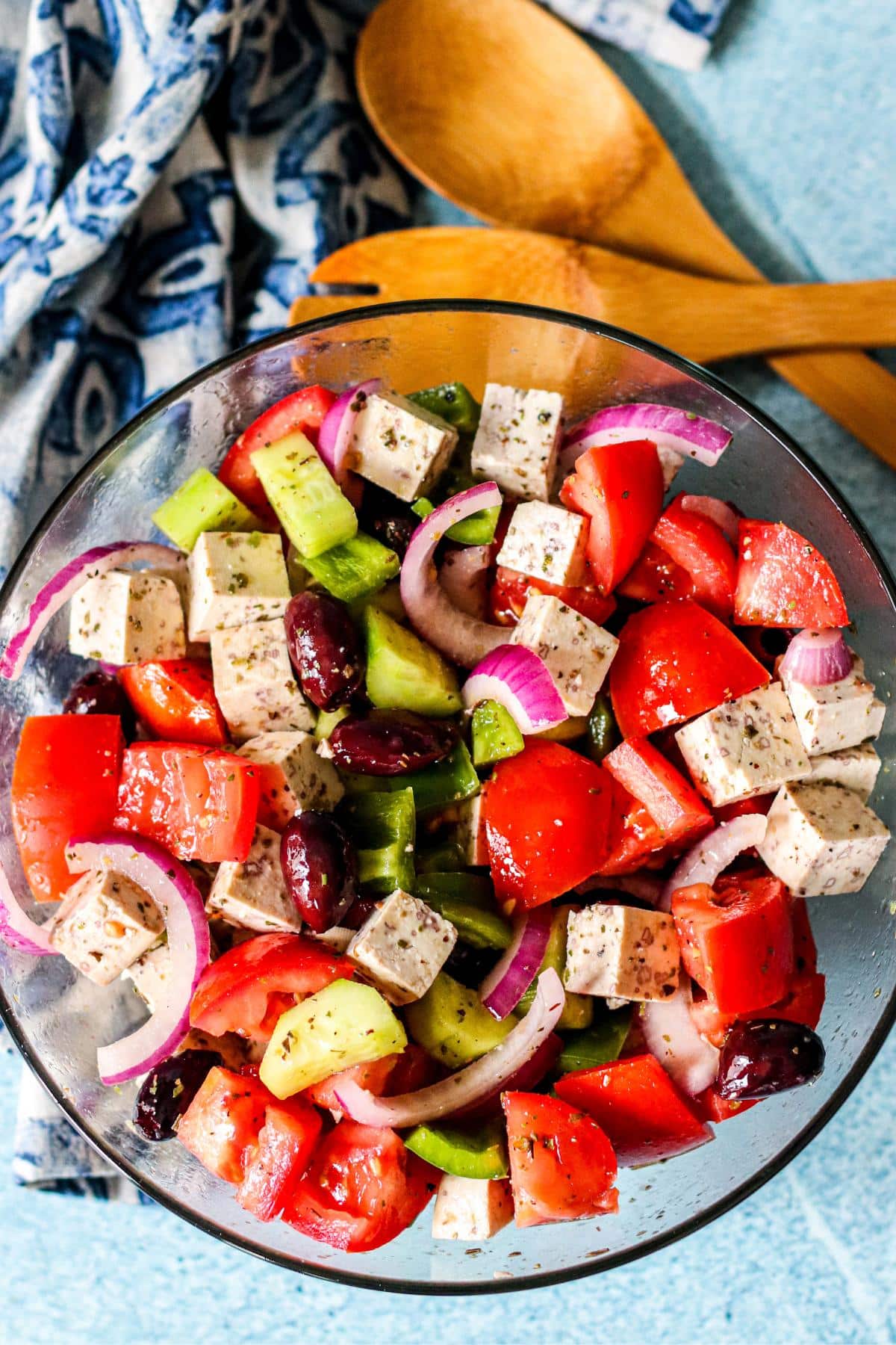 Serving bowl of salad made with tomatoes, cucumbers, red onions, green bell peppers, Kalamata olives, and tofu feta.
