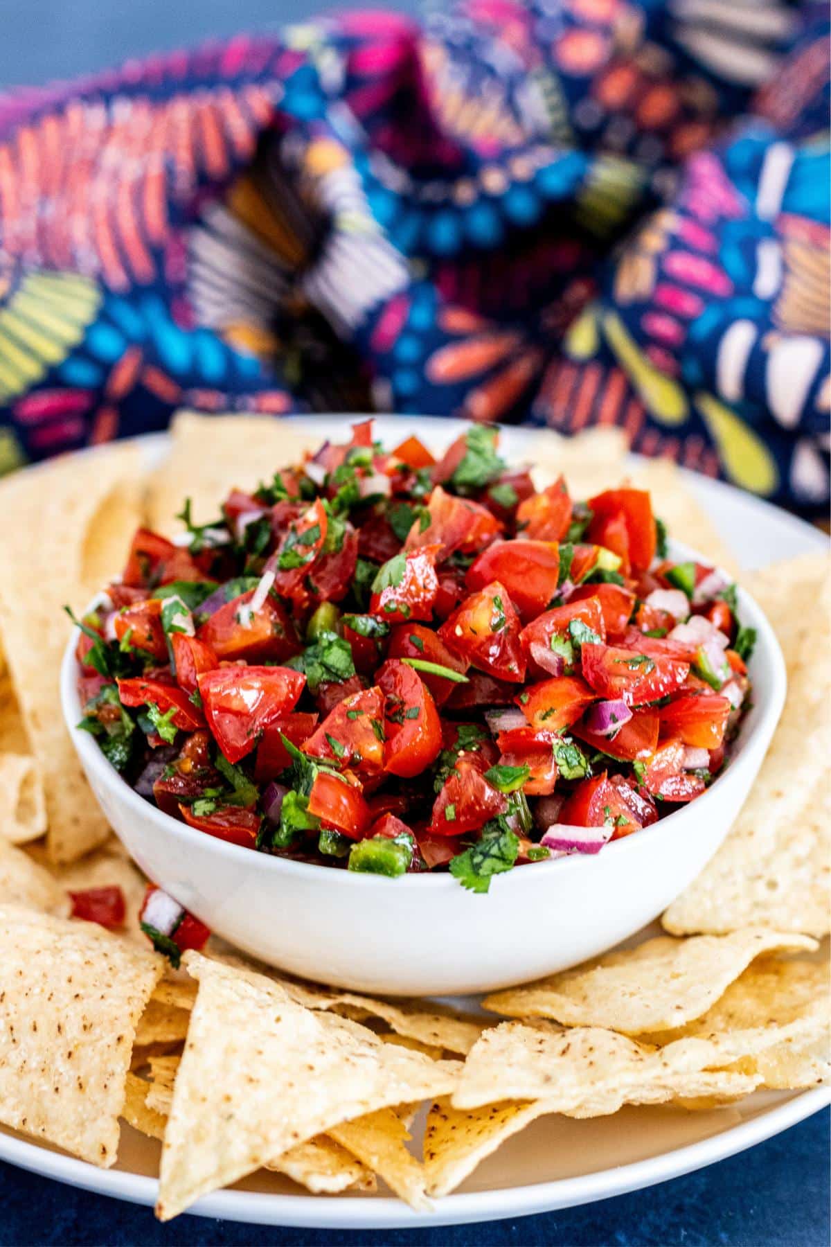 Bowl of salsa on a plate with tortilla chips.