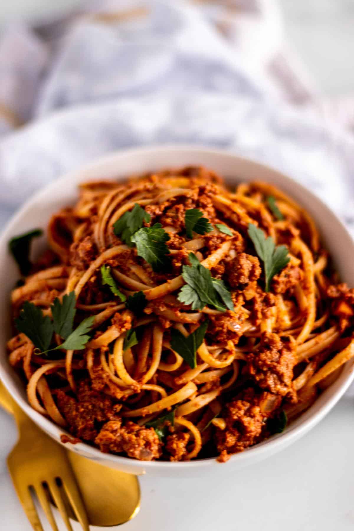Bowl of linguine tossed with vegan meat sauce and topped with fresh parsley.