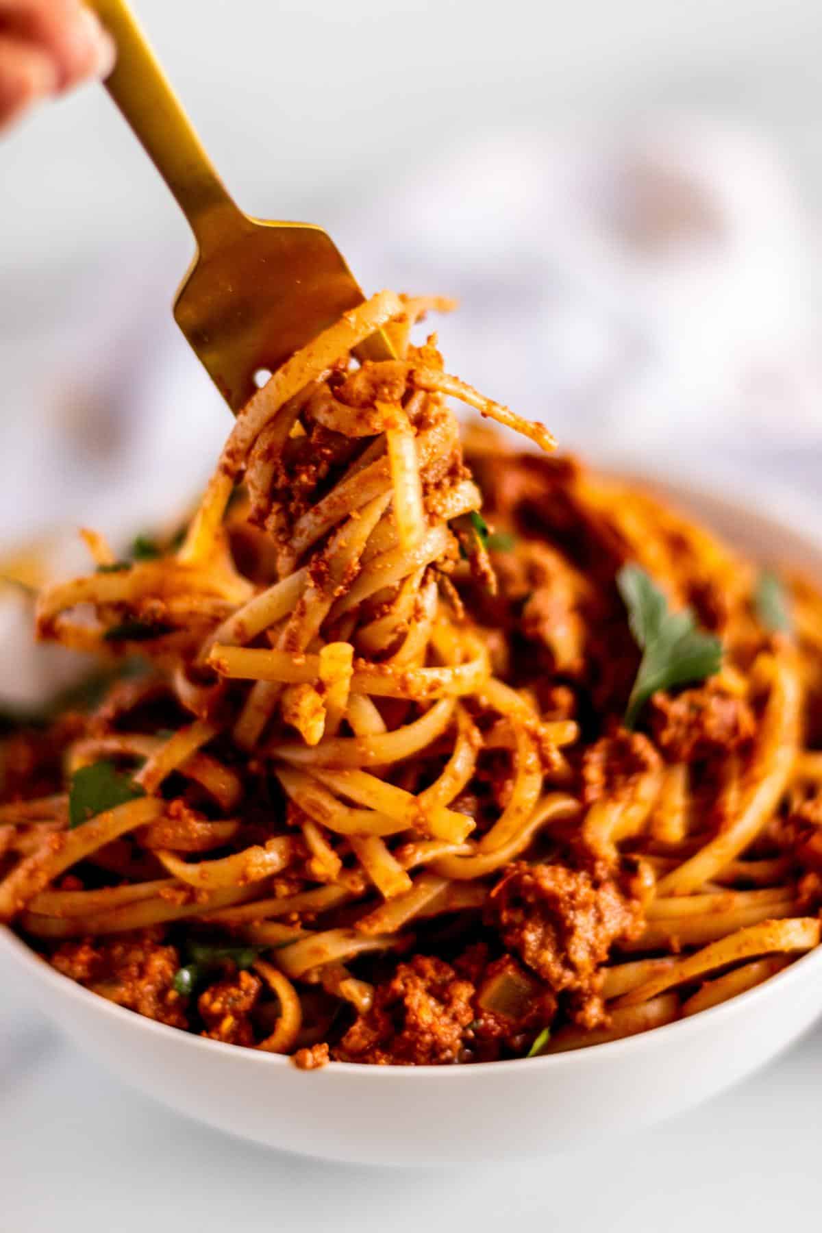 A fork twirling a bite of pasta over a bowl.