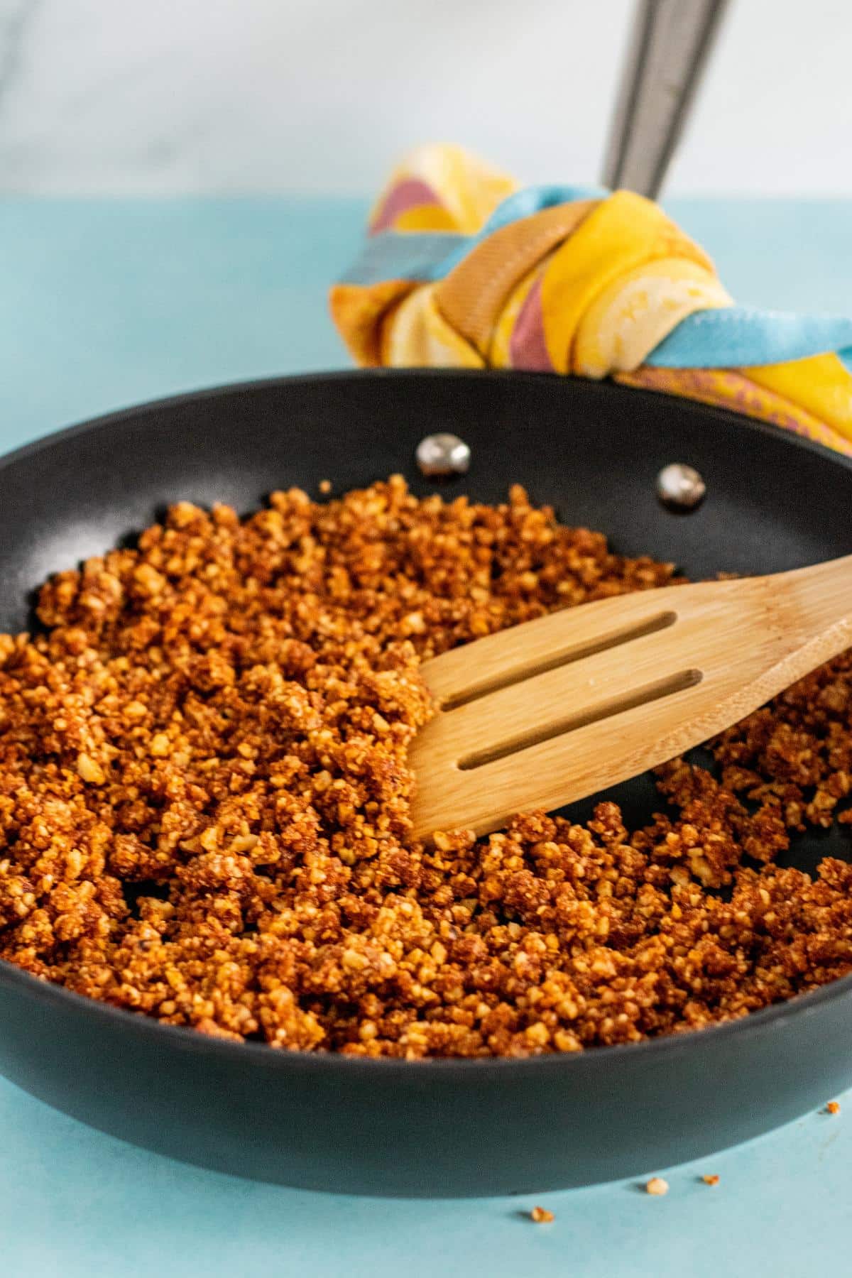 Heating the walnut meat crumbles in a skillet.
