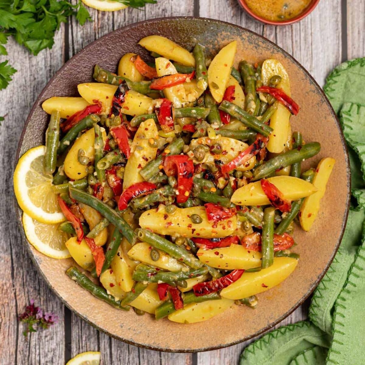 Serving bowl of Green Bean Potato Salad garnished with lemon slices.