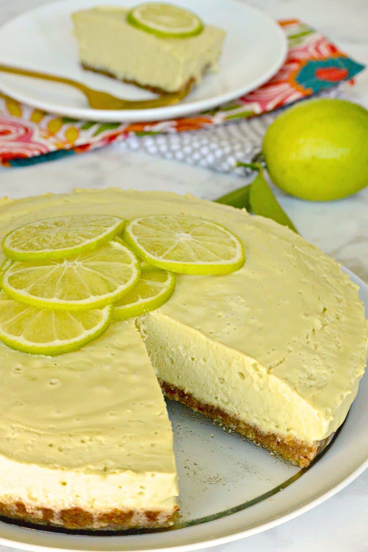 Raw lime pie on a platter with a slice removed.