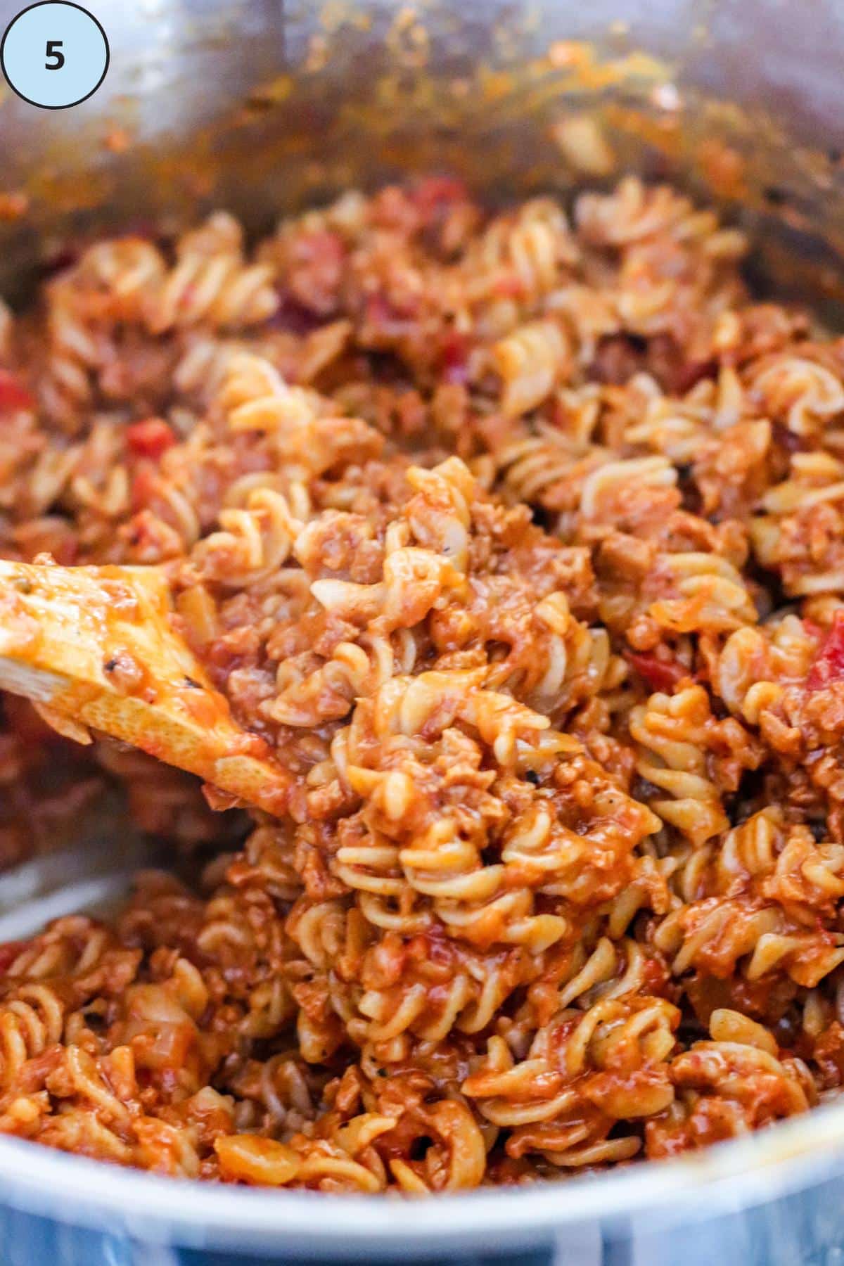 Folding the cooked pasta into the sauce.