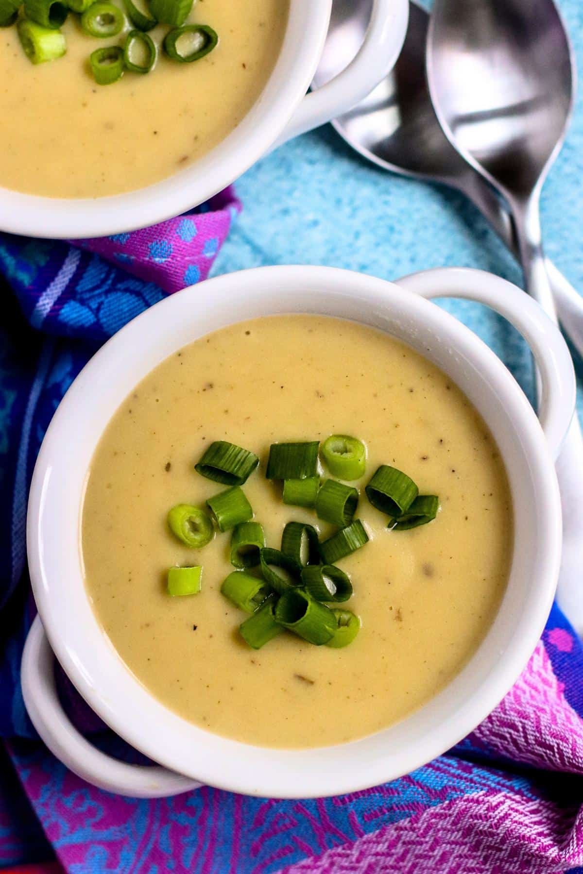 Bowls of potato leek soup topped with sliced green onions.