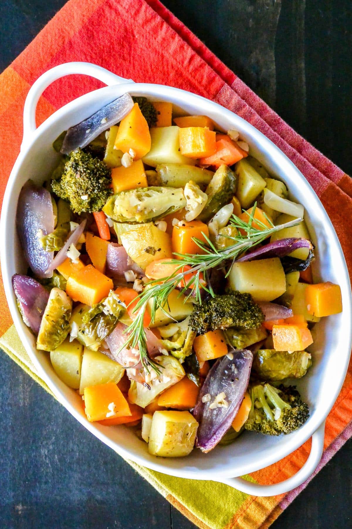 White Wine Roasted Vegetables in a baking dish garnished with a sprig of fresh rosemary.