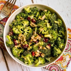 Bowl of Vegan Broccoli Cranberry Salad with a fork on a paisley napkin.