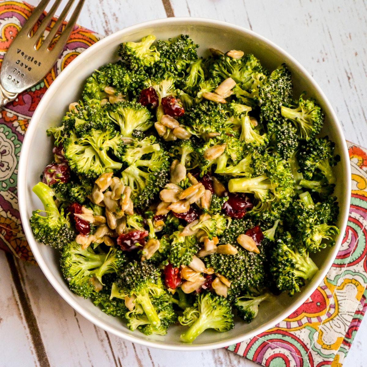Bowl of Vegan Broccoli Cranberry Salad with a fork on a paisley napkin.