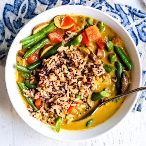 Bowl of green bean curry with rice and a spoon.