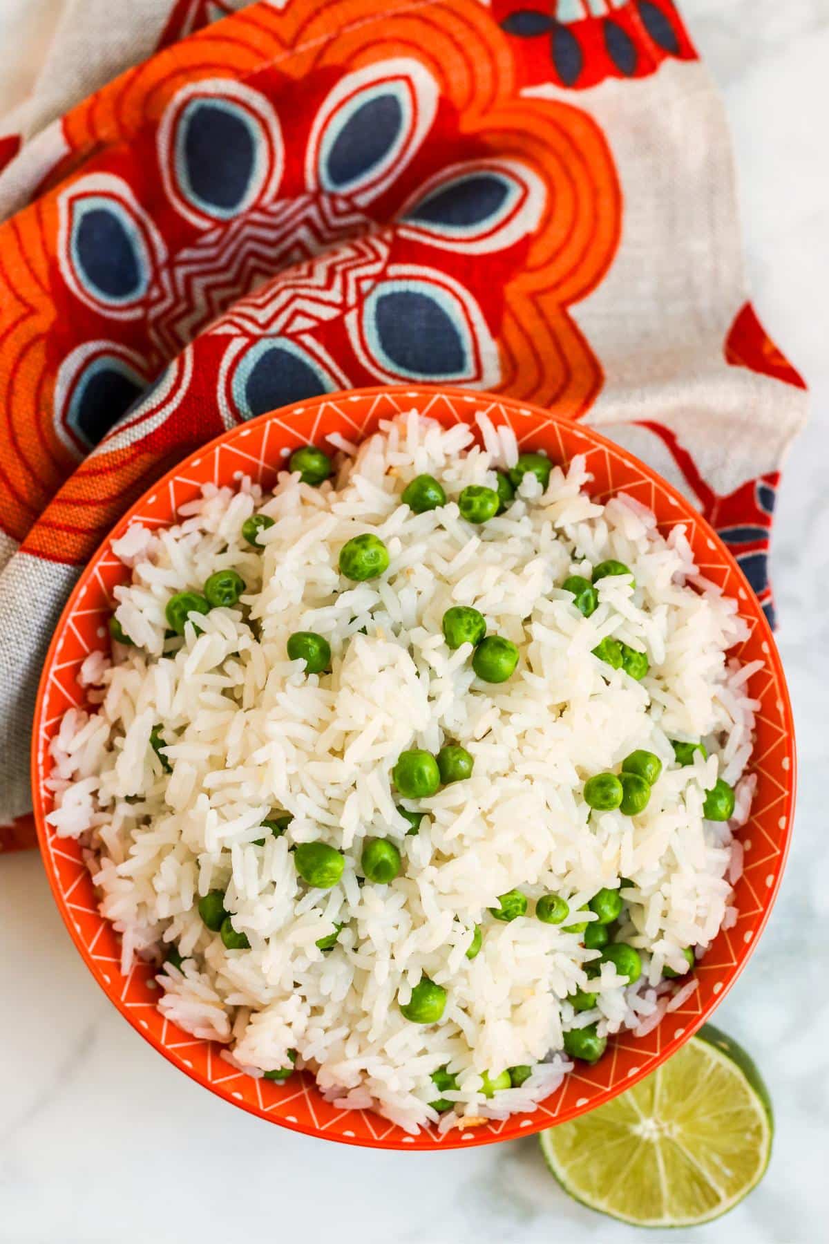 Bowl of coconut rice and peas with half a lime next to it.