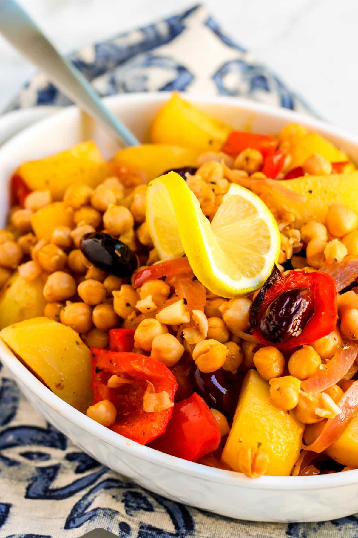 Serving spoon in a dish of roasted potatoes and chickpeas.