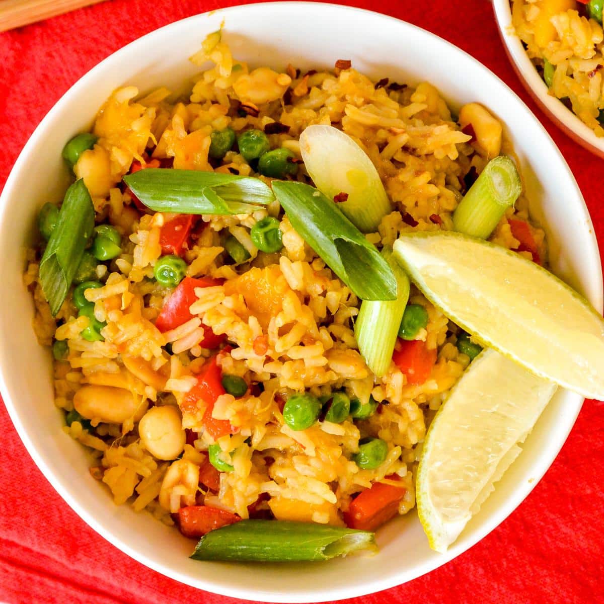 Bowl of mango fried rice garnished with lime wedges.