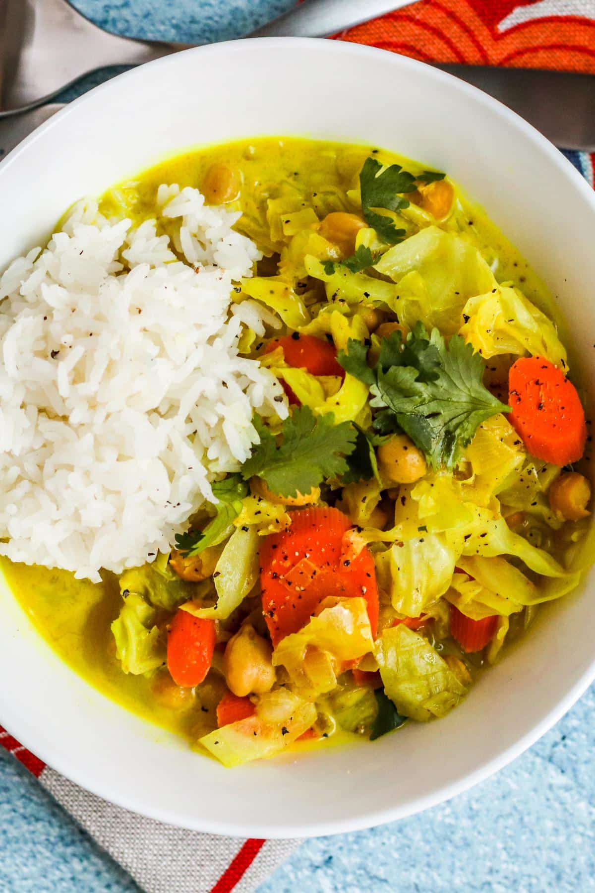 Bowl of curry served with a scoop of rice on top.