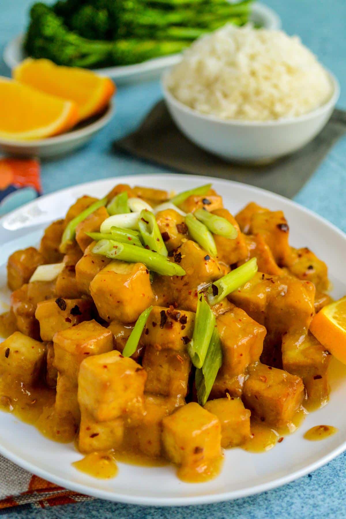 Orange Tofu on a plate garnished with sliced green onions.