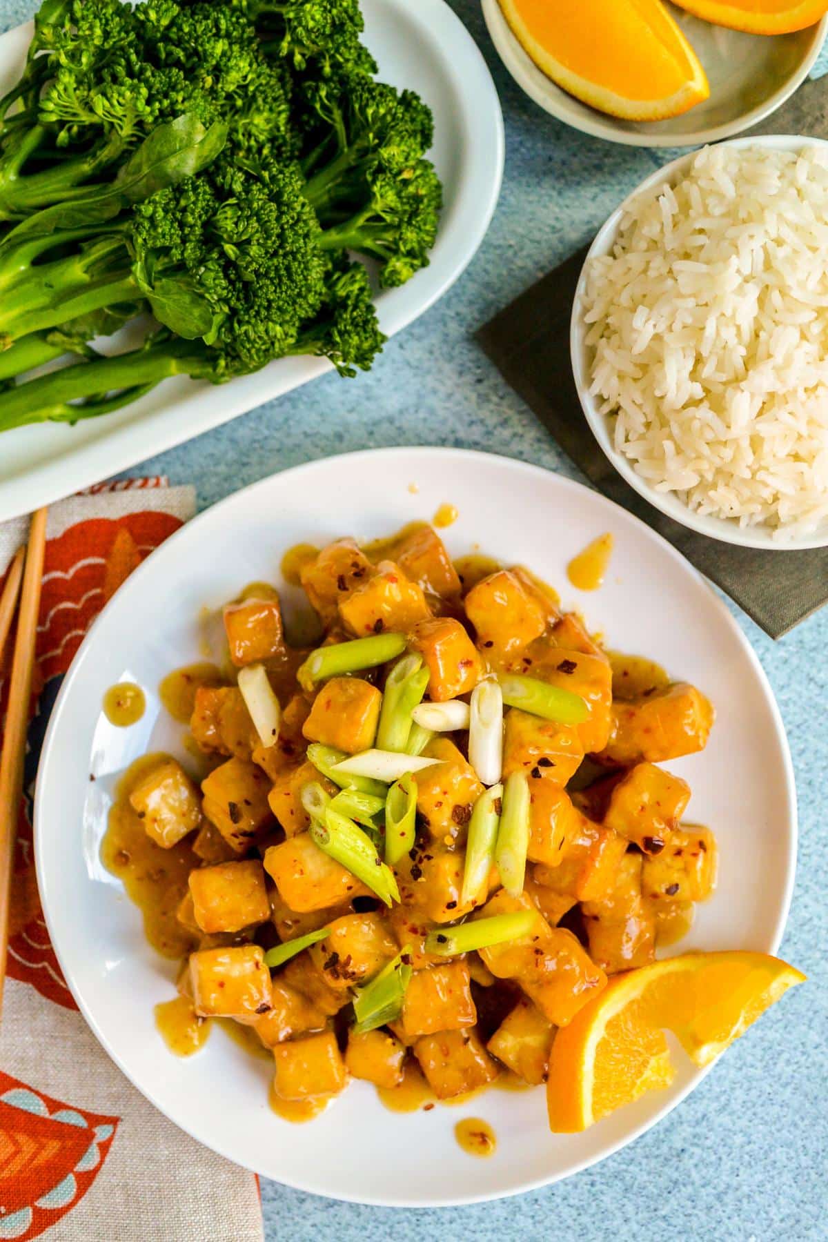 Plate with steamed broccoli, bowl of rice, and plate of air fryer orange tofu.