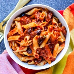 Bowl of penne with vegan puttanesca sauce.