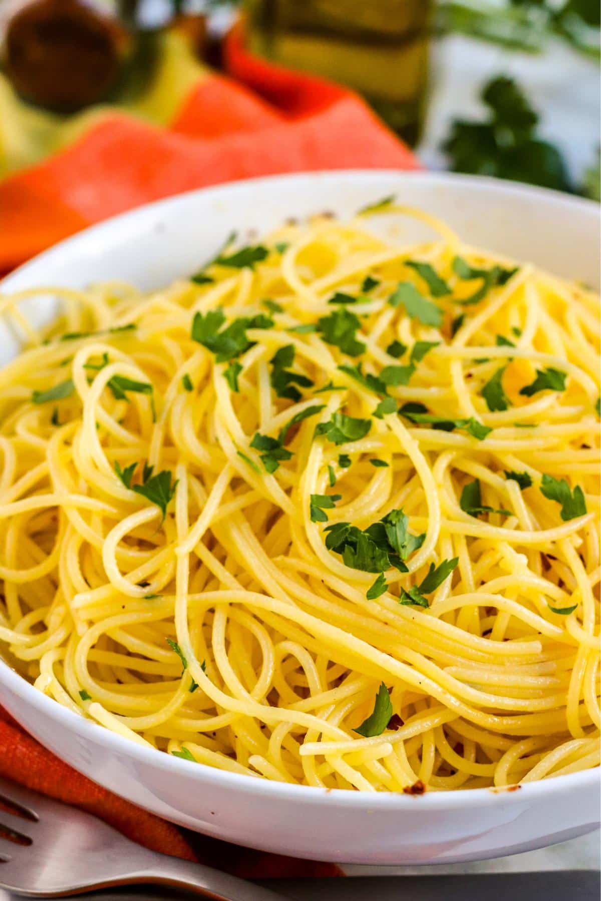 Bowl of olive oil garlic pasta topped with chopped parsley.