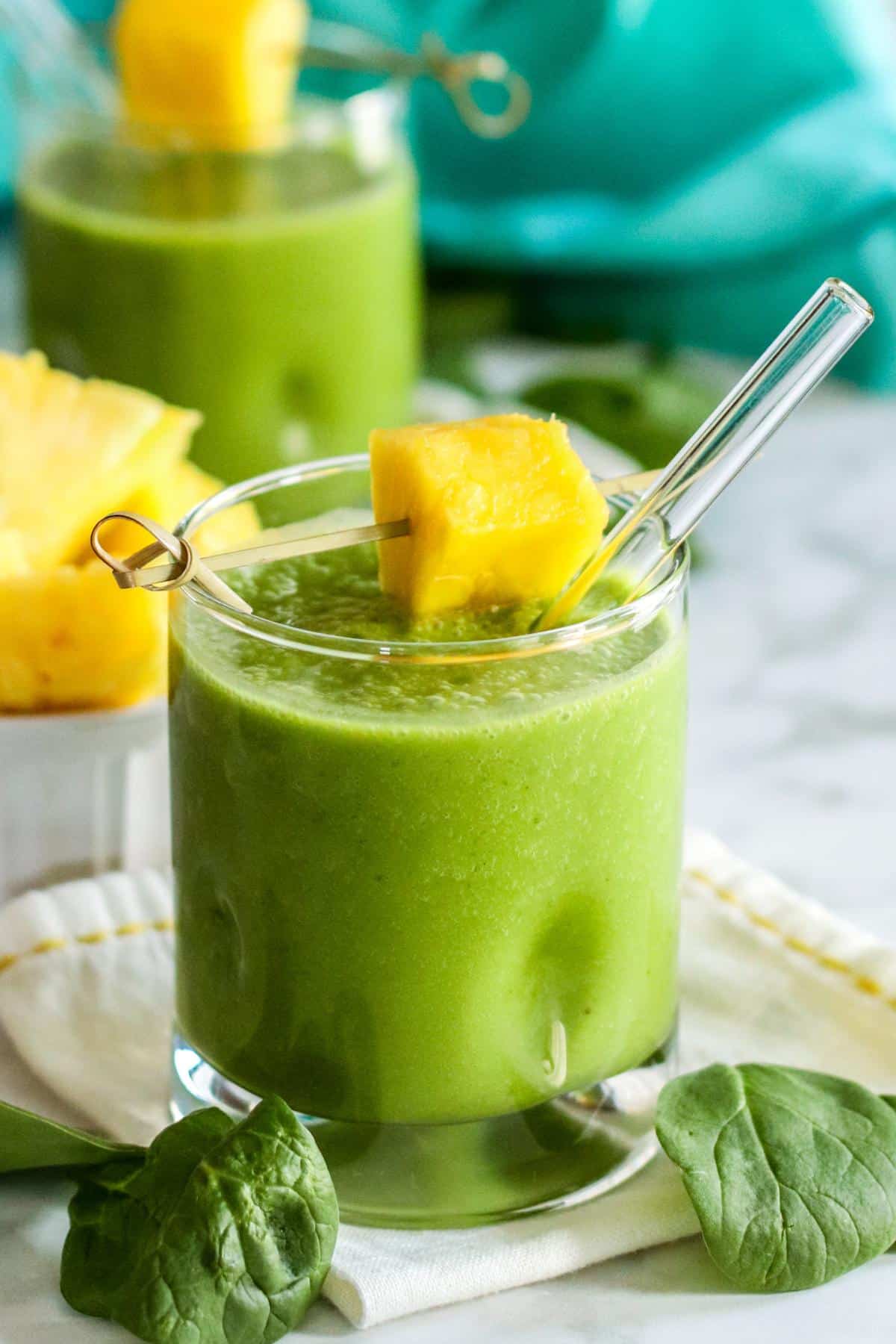 Pineapple green smoothies in glasses garnished with fresh pineapple.