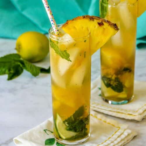 Pineapple mojitos in tall glasses garnished with pineapple wedges.