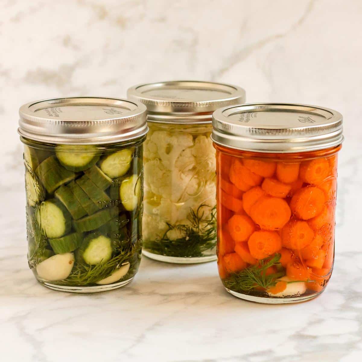 Jars of pickled cucumbers, cauliflower, and carrots.