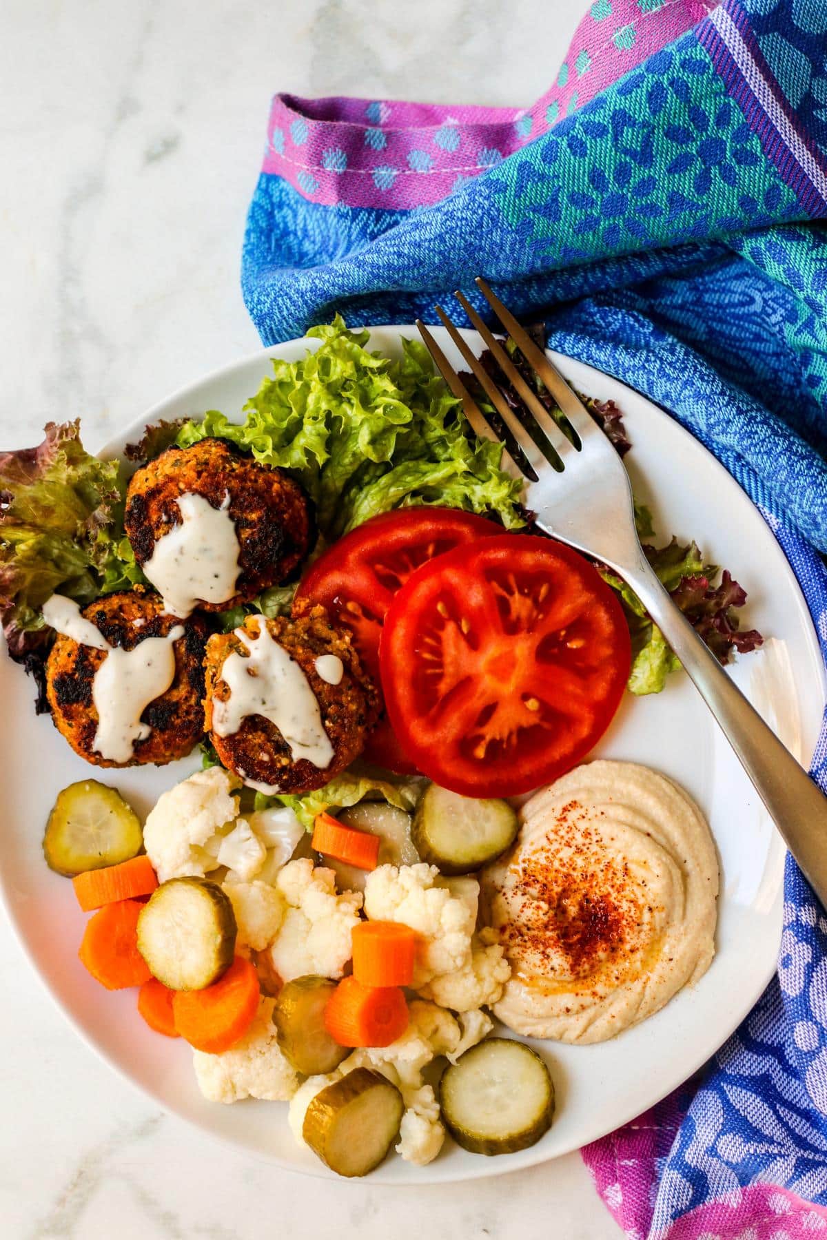 Plate of falafel, lettuce, tomatoes, hummus, and refrigerator pickled vegetables.