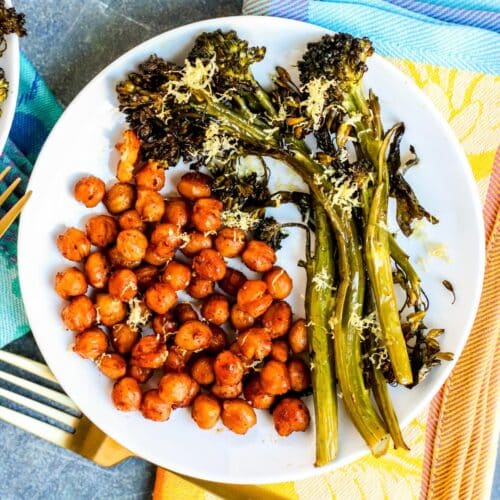 Dinner plate with roasted chickpeas and broccolini topped with lemon zest.
