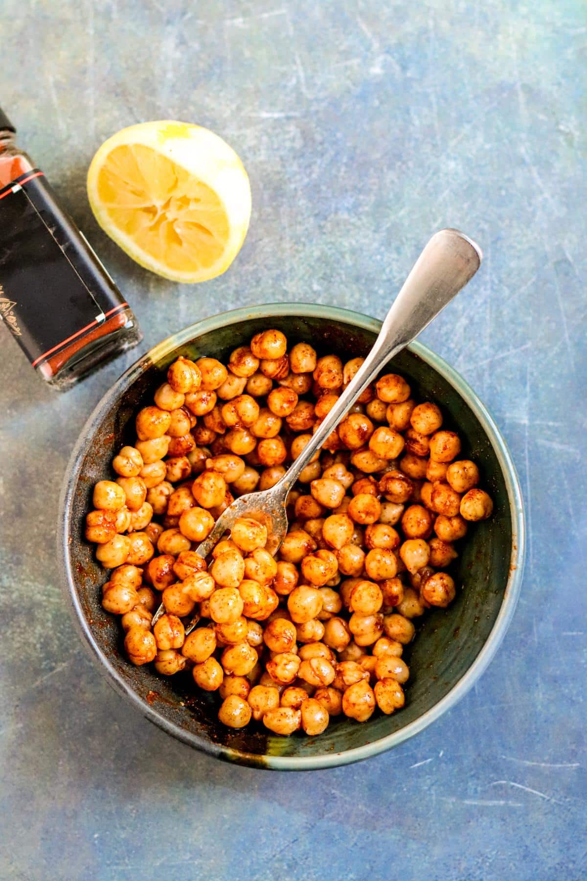 Bowl of chickpeas, bottle of smoked paprika, and half a zested and juiced lemon.