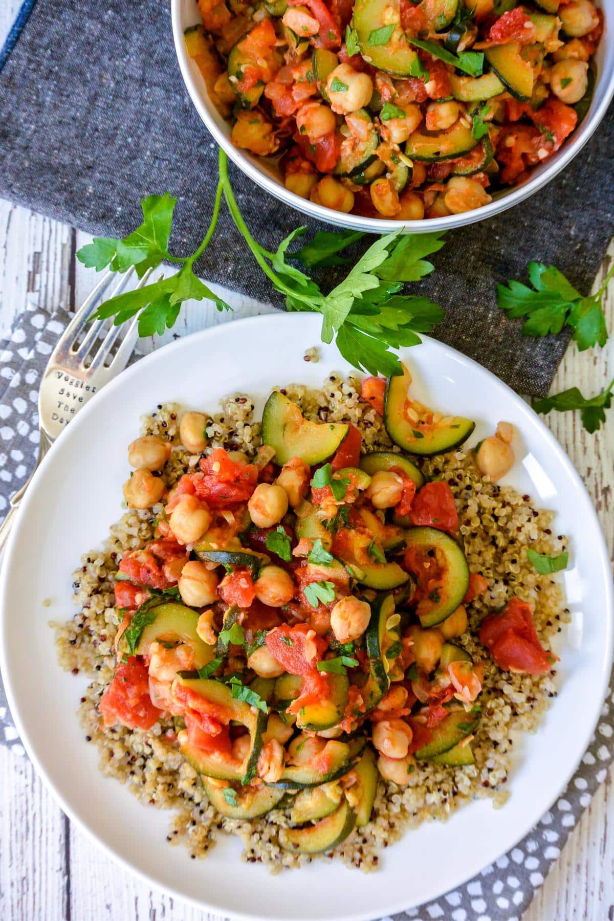 Plate of quinoa topped with stewed zucchini and tomatoes.