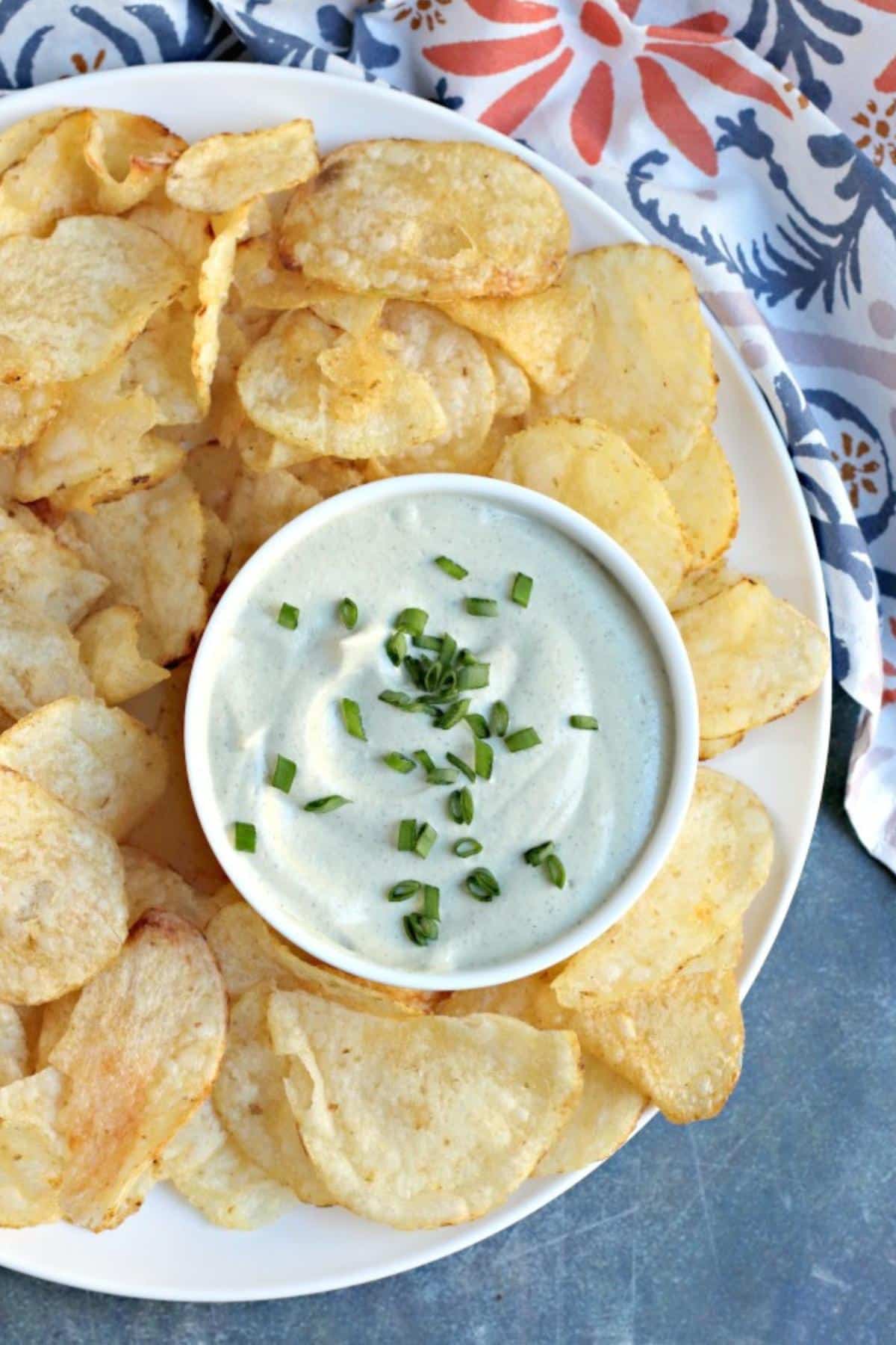 Potato chips on a platter with a bowl of dip.