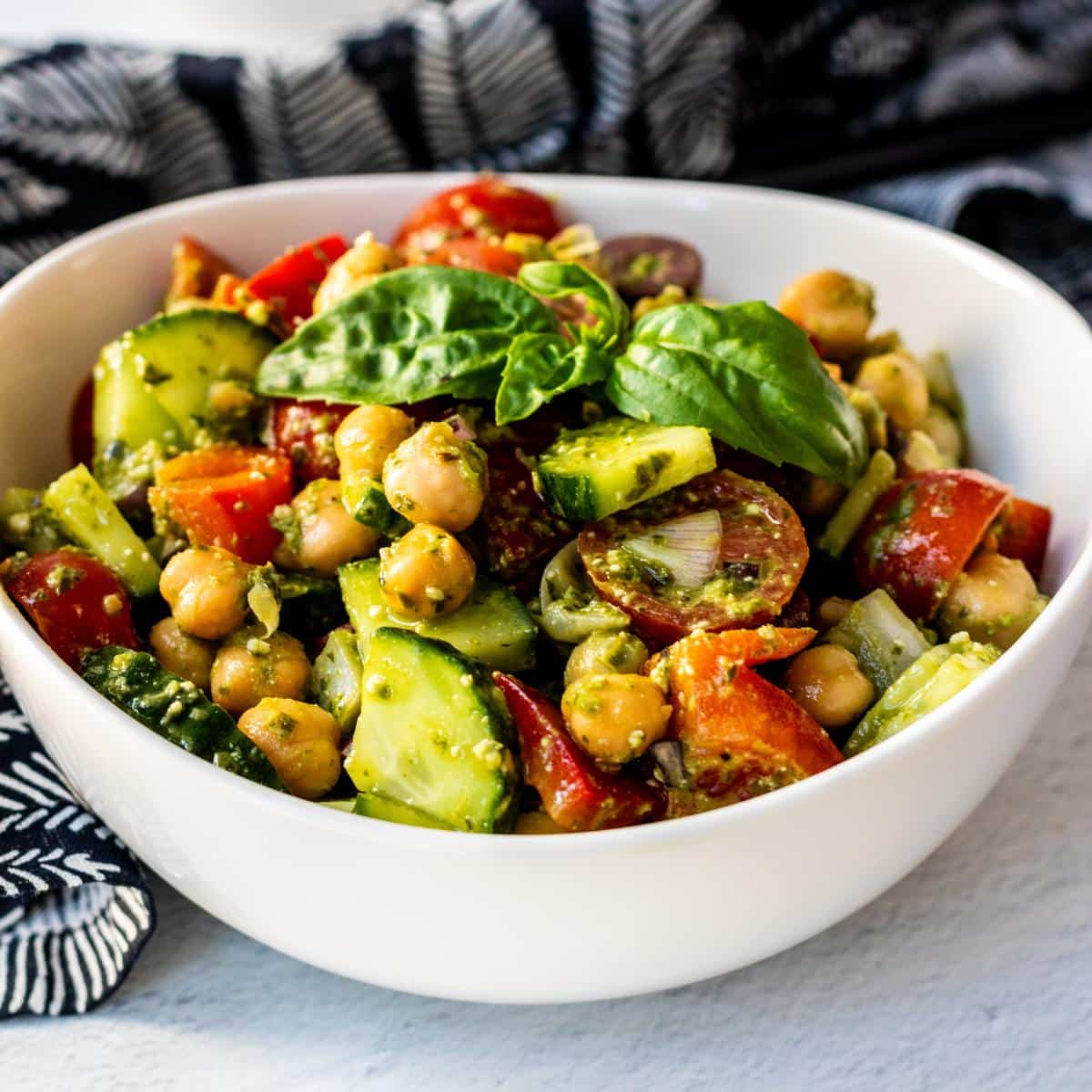 Bowl of Vegan Pesto Chickpea Salad garnished with a sprig of basil.