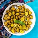 Bowl of pesto potatoes garnished with basil leaves.