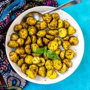 Bowl of pesto potatoes garnished with basil leaves.