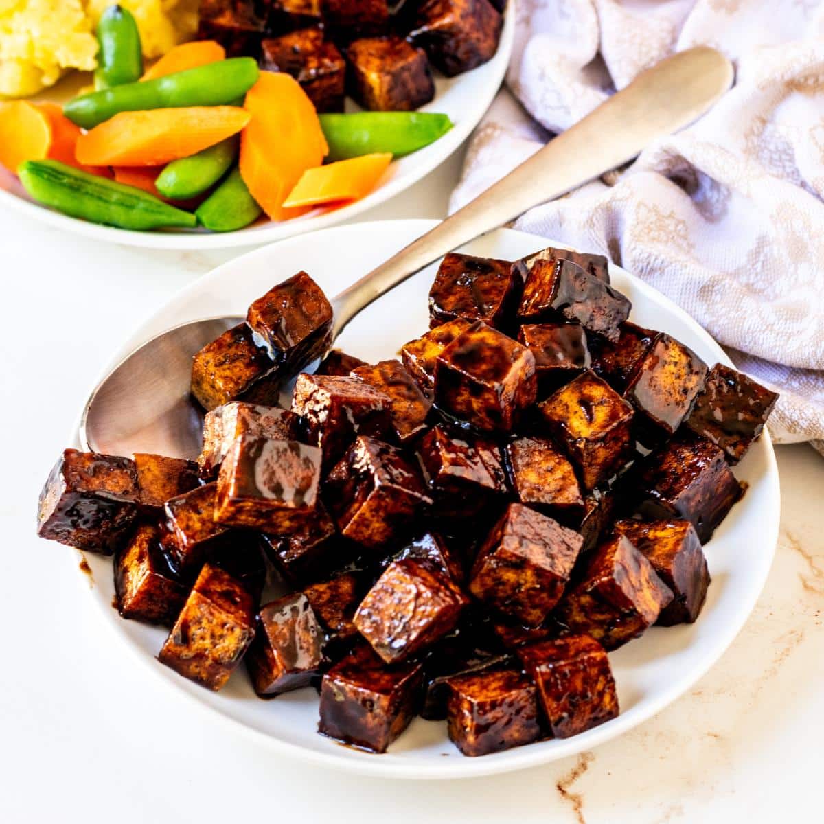 Plate of tofu cubes in a deep brown sauce.