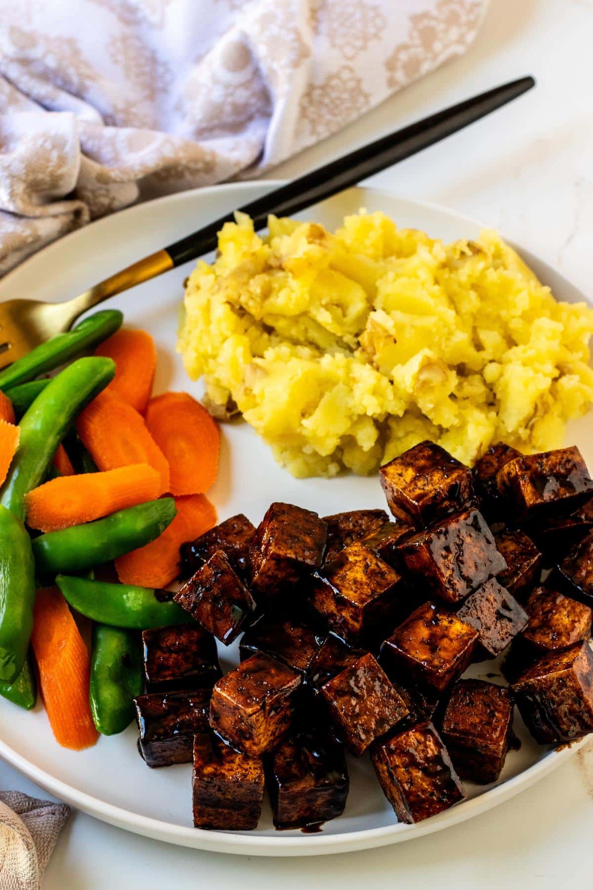 Dinner plate with balsamic tofu, mashed potatoes, and steamed sugar snap peas and carrots.