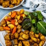 Rosemary tofu on a dinner plate with roasted potatoes and carrots and a green salad.
