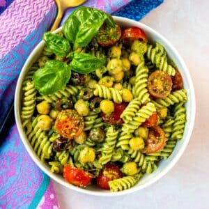 Bowl of Vegan Pesto Pasta Salad garnished with a sprig of fresh basil.