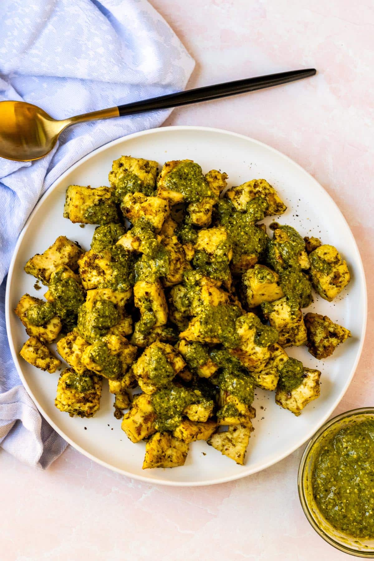 Plate of crispy baked tofu drizzled with extra pesto sauce.