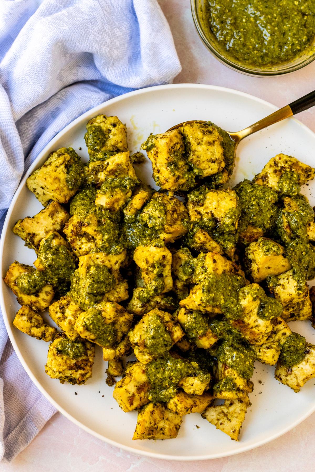 Plate of baked tofu drizzled with extra pesto sauce.