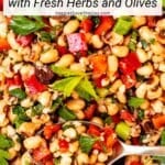 Spoon in a bowl of bean salad with text overlay: Mediterranean Black Eyed Pea Salad with Fresh Herbs and Olives.