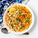 Bowl of bean soup garnished with a lemon wedge.