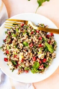 Plate with pomegranate quinoa salad and a gold fork.