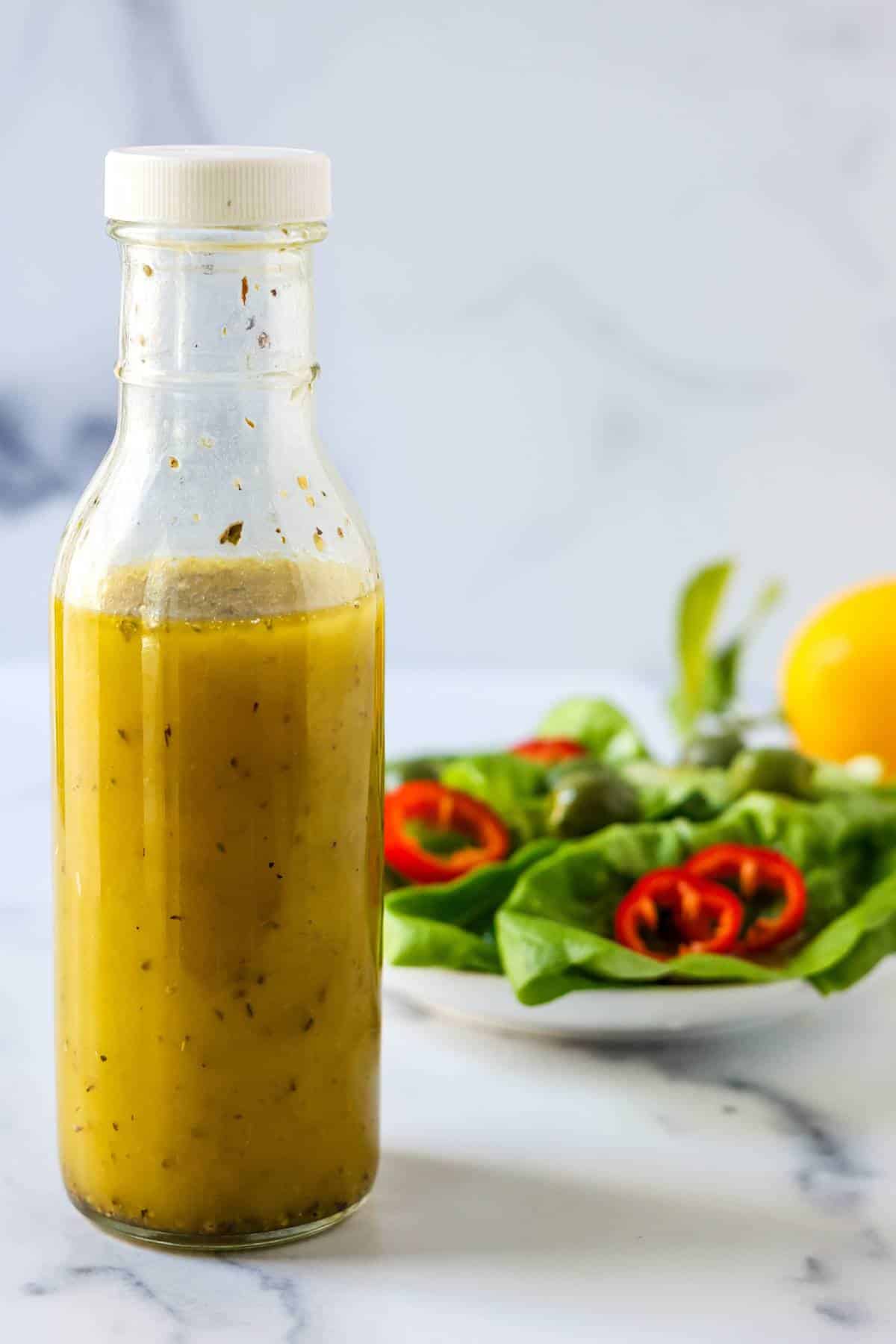 Bottle of dressing, a salad, and a lemon.