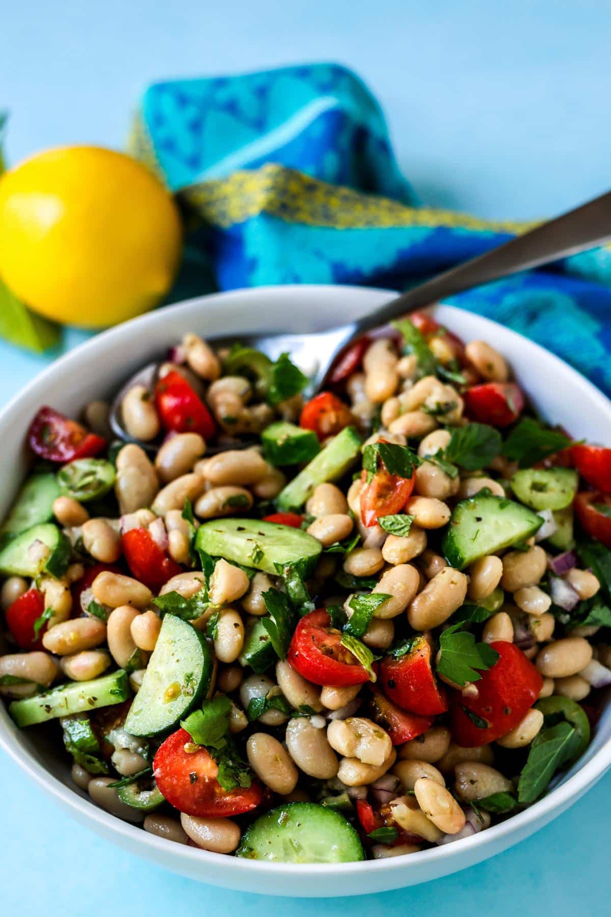 Mediterranean white bean salad in a large serving bowl with a spoon.