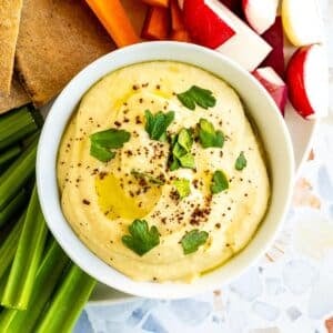 Bowl of hummus garnished with fresh parsley and ground sumac.