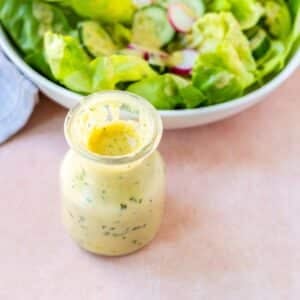 Jar of dressing and a green salad.