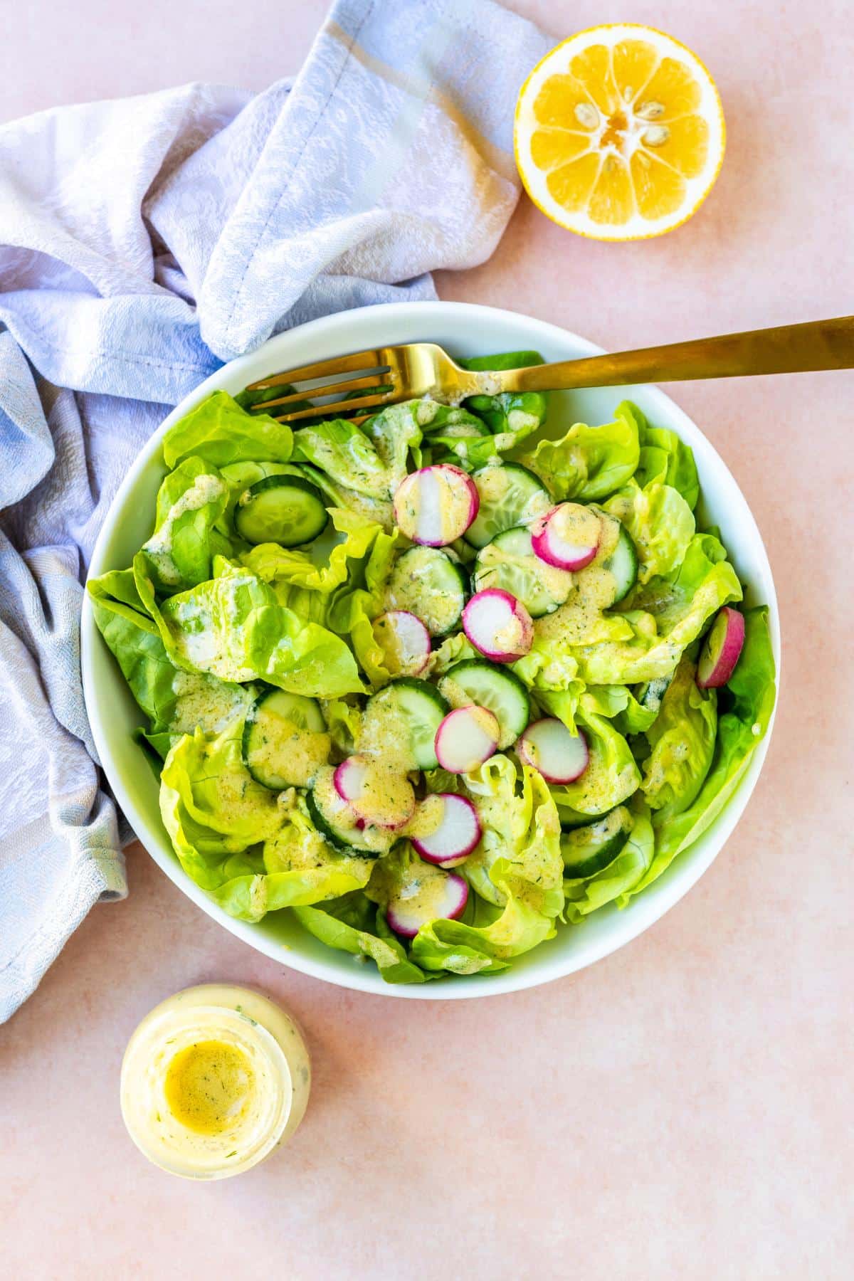 Half a lemon, a bowl of salad, and a bottle of dressing.