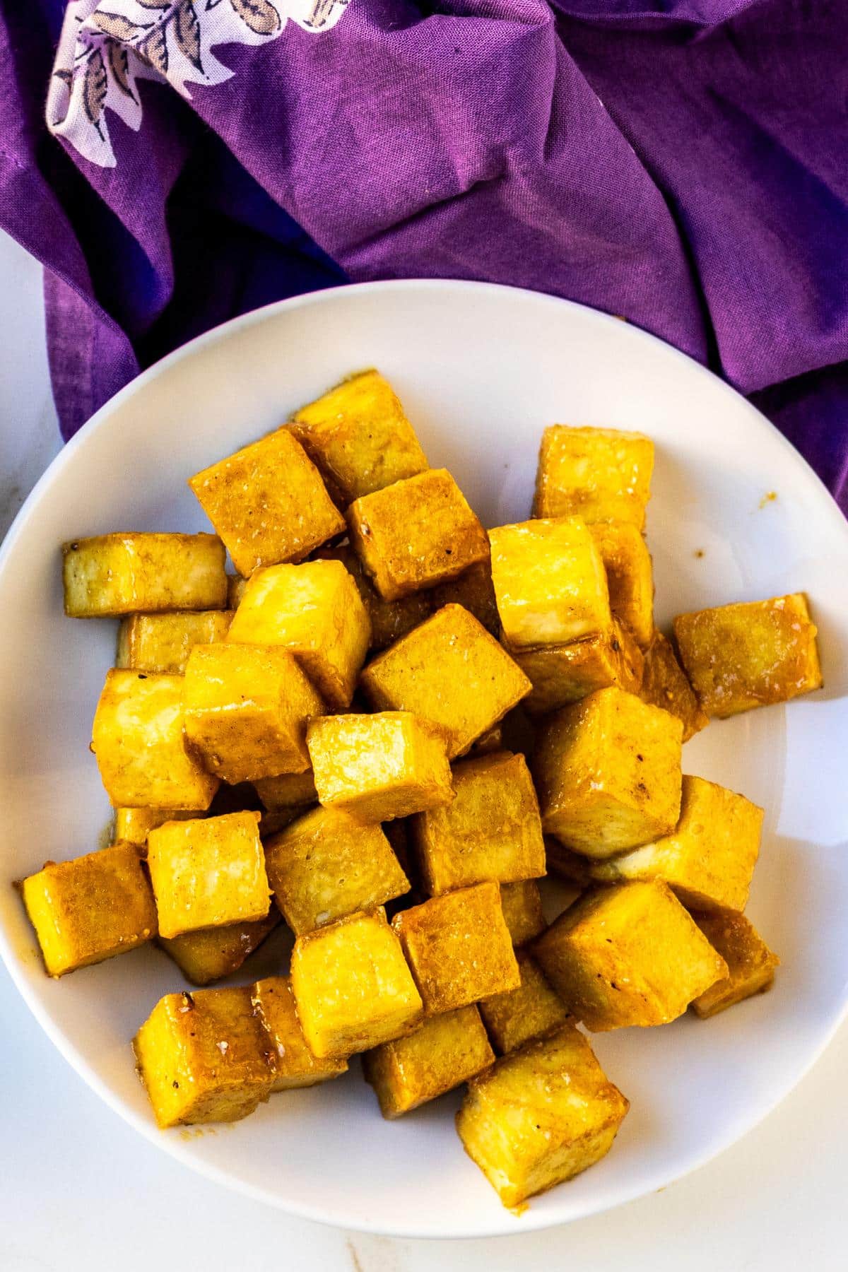 Plate of crispy maple Dijon tofu cubes and a purple napkin.